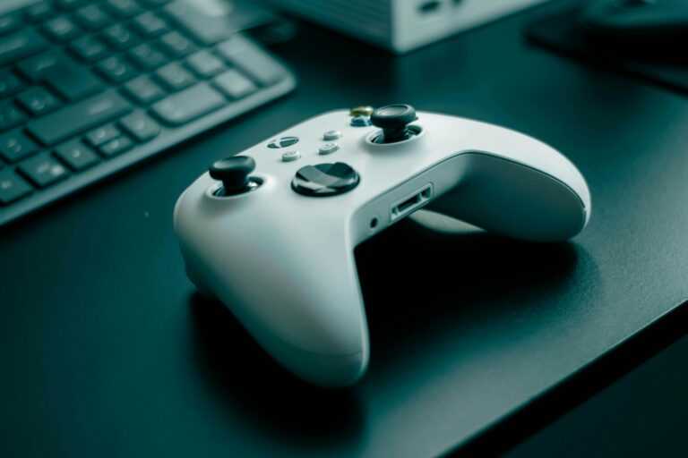 Close-up of a white game controller on a sleek desk, highlighting technology and gaming.