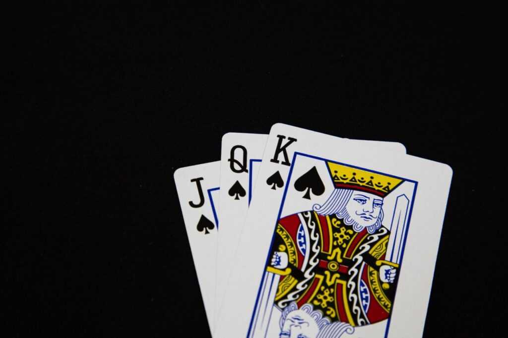 Close-up of Jack, Queen, King of Spades playing cards on black background.